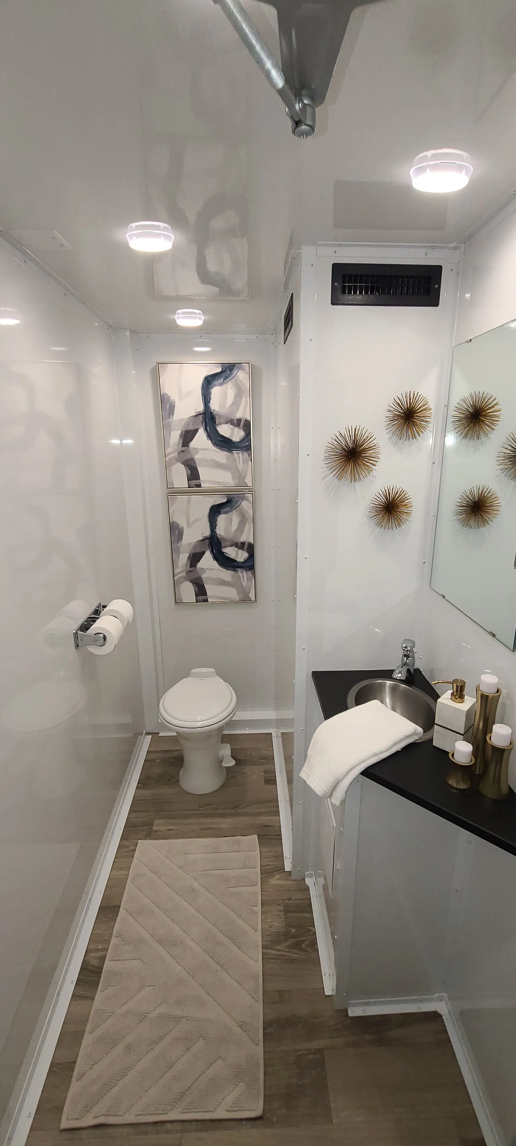 Spacious women's restroom stall featuring flushing toilet, vanity sink with mirror, and climate-controlled interior