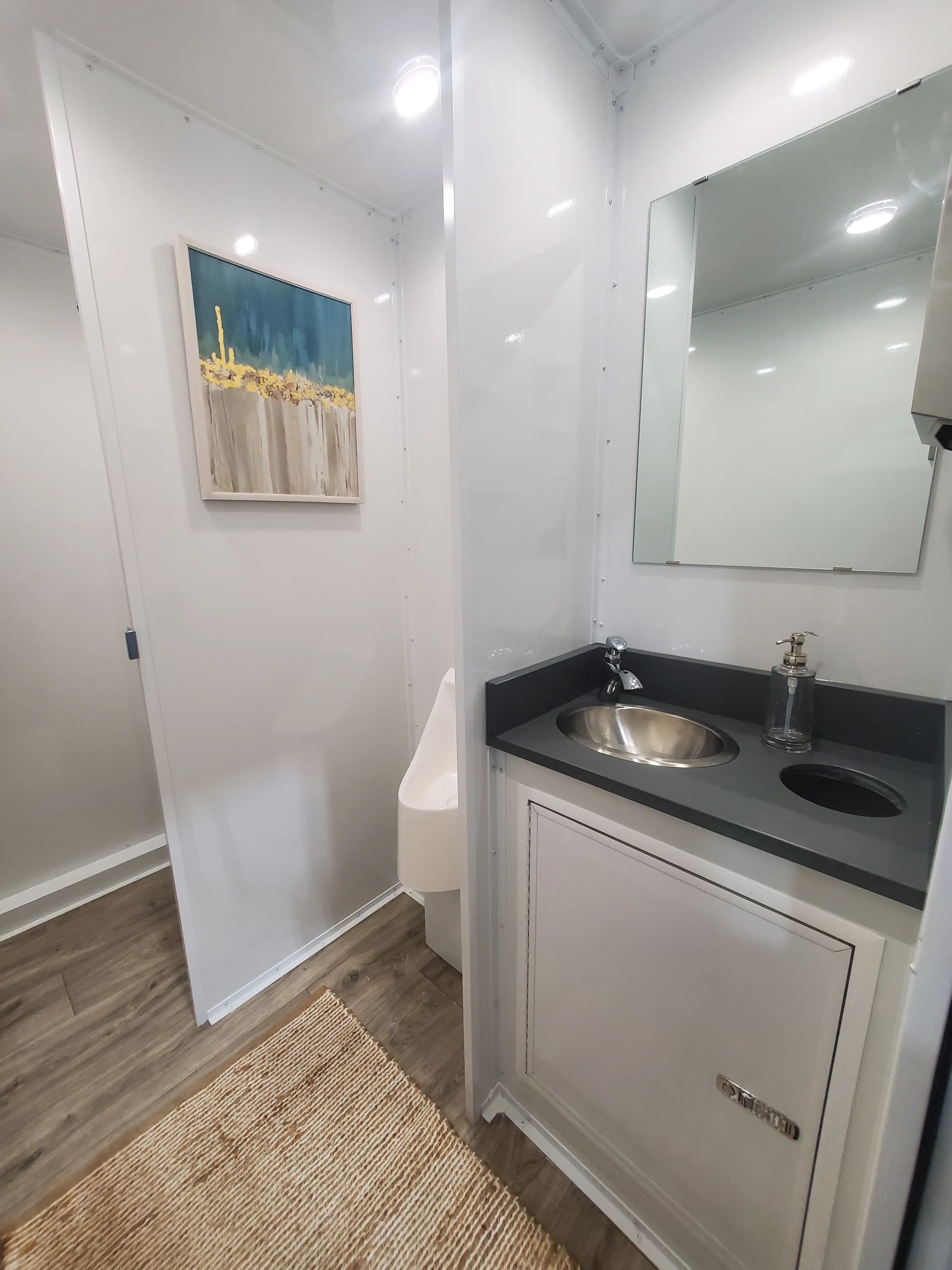 Men's restroom with two private stalls including flushing toilet, urinal, and hand washing station