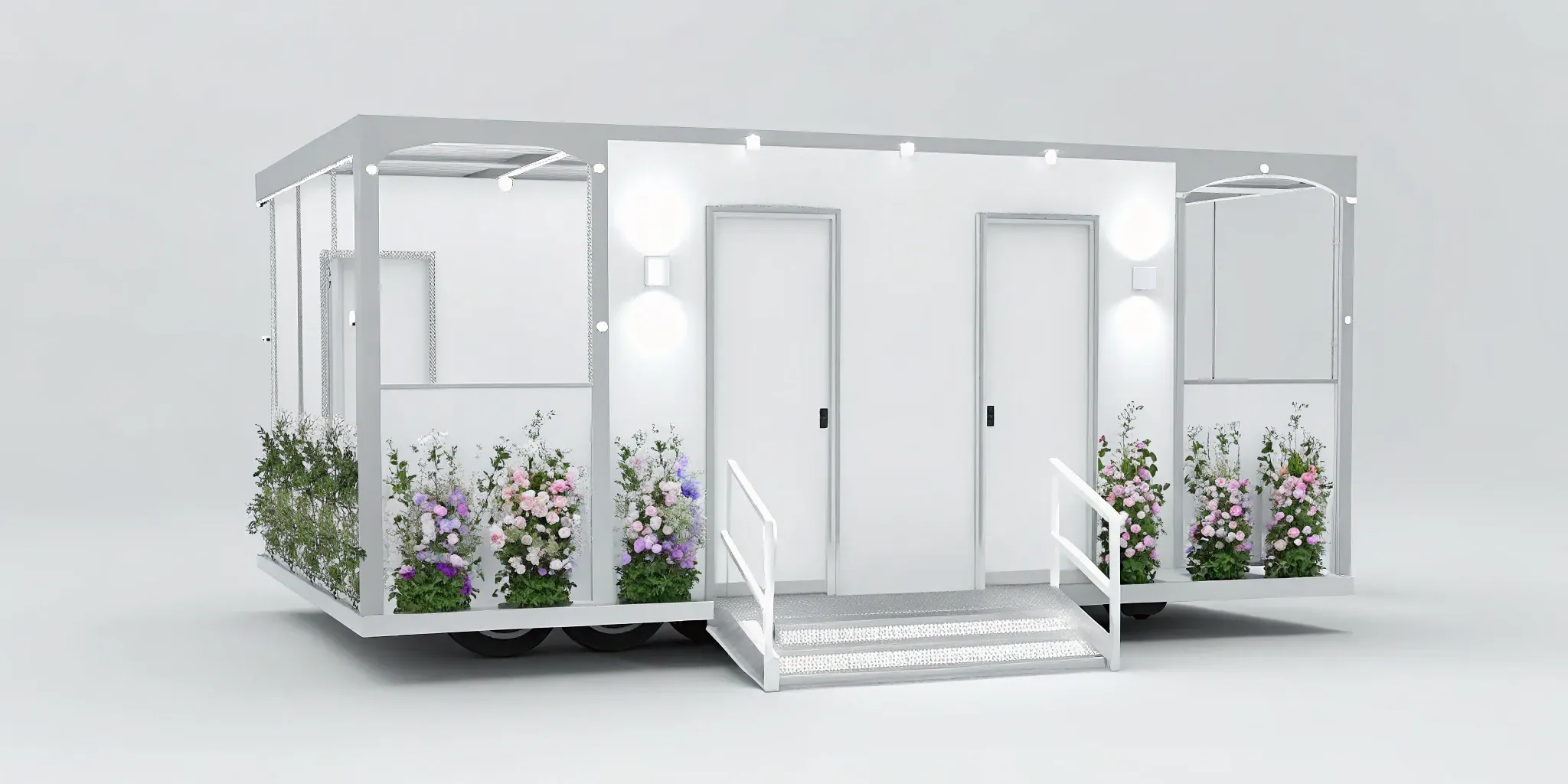 A modern white luxury portable toilet trailer decorated with flowers for a wedding.
